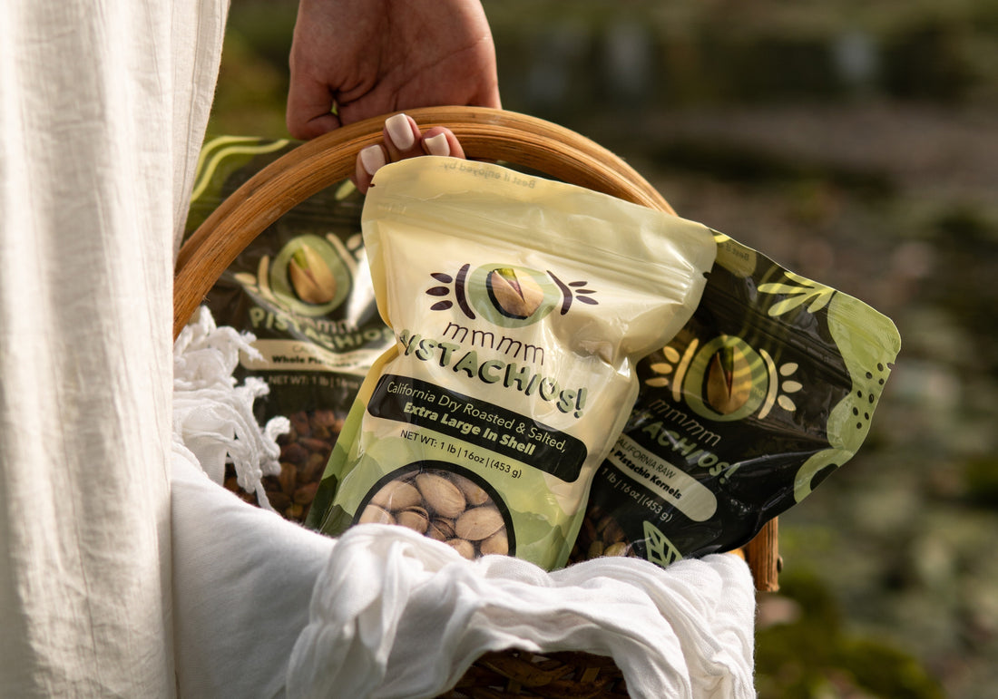 Raw (pasteurized) and roasted pistachios by MMMM Good Foods in a wooden basket held by a woman.